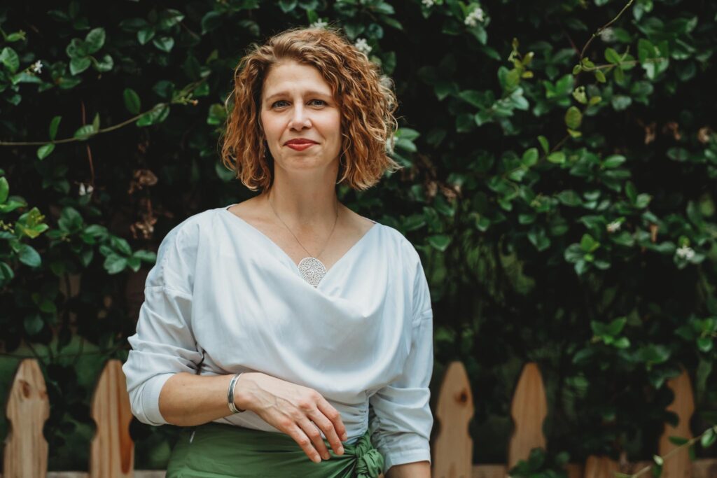 photo of a serene Sea Stachura standing before a  green background